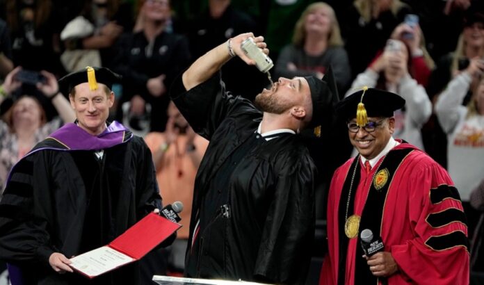 Travis Kelce drinking beer while receiving diploma